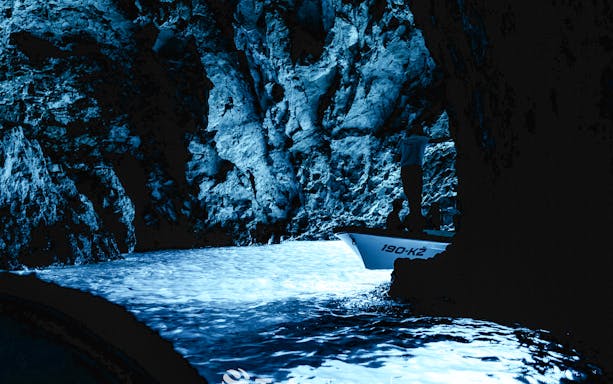 Inside view of the Blue Cave, highlighting the shimmering blue waters and unique rock formations, Croatia.