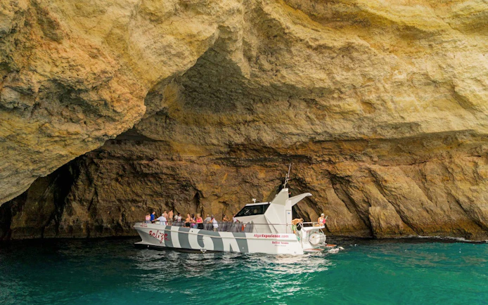 Tourists on a catamaran entering Benagil Caves, Algarve, Portugal.