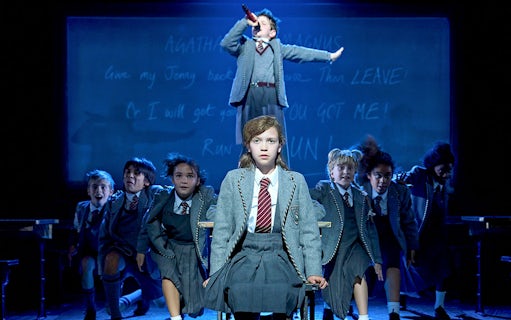 Children performing a scene from Matilda The Musical on stage.