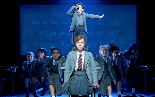 Children performing a scene from Matilda The Musical on stage.