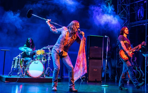 Rock band performing on stage with vibrant lighting, related to "Almost Famous" tour.
