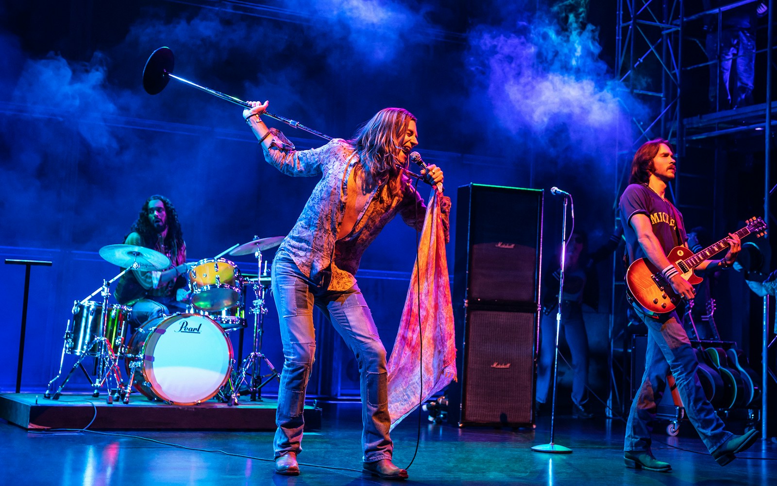 Rock band performing on stage with vibrant lighting, related to "Almost Famous" tour.