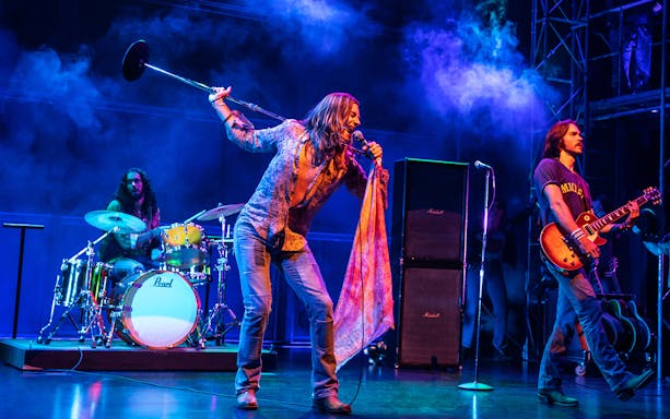 Rock band performing on stage with vibrant lighting, related to "Almost Famous" tour.