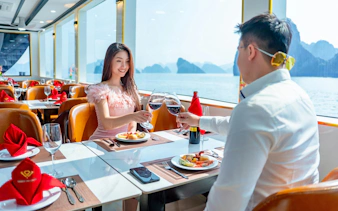 Couple toasting wine on Ha Long Bay luxury cruise with scenic view.