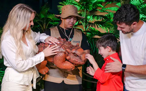 Visitors interacting with a dinosaur model at Dinosaurs: The Immersive Odyssey VR Experience.