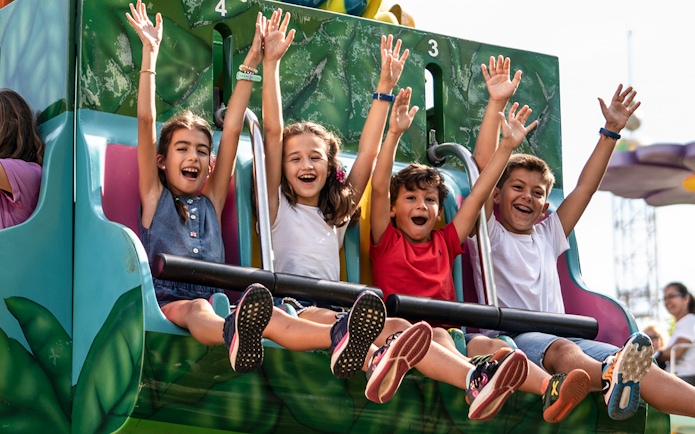 Children enjoying a ride at Isla Mágica, Seville, with arms raised in excitement.