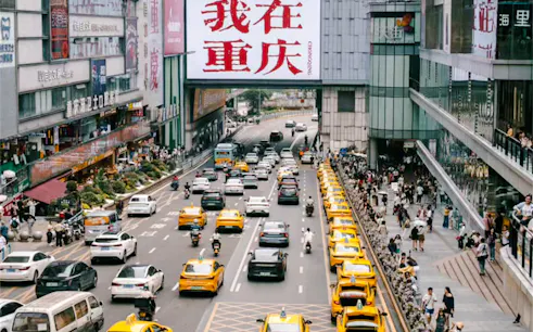 Busy street in Chongqing with yellow taxis and pedestrians, showcasing urban life.