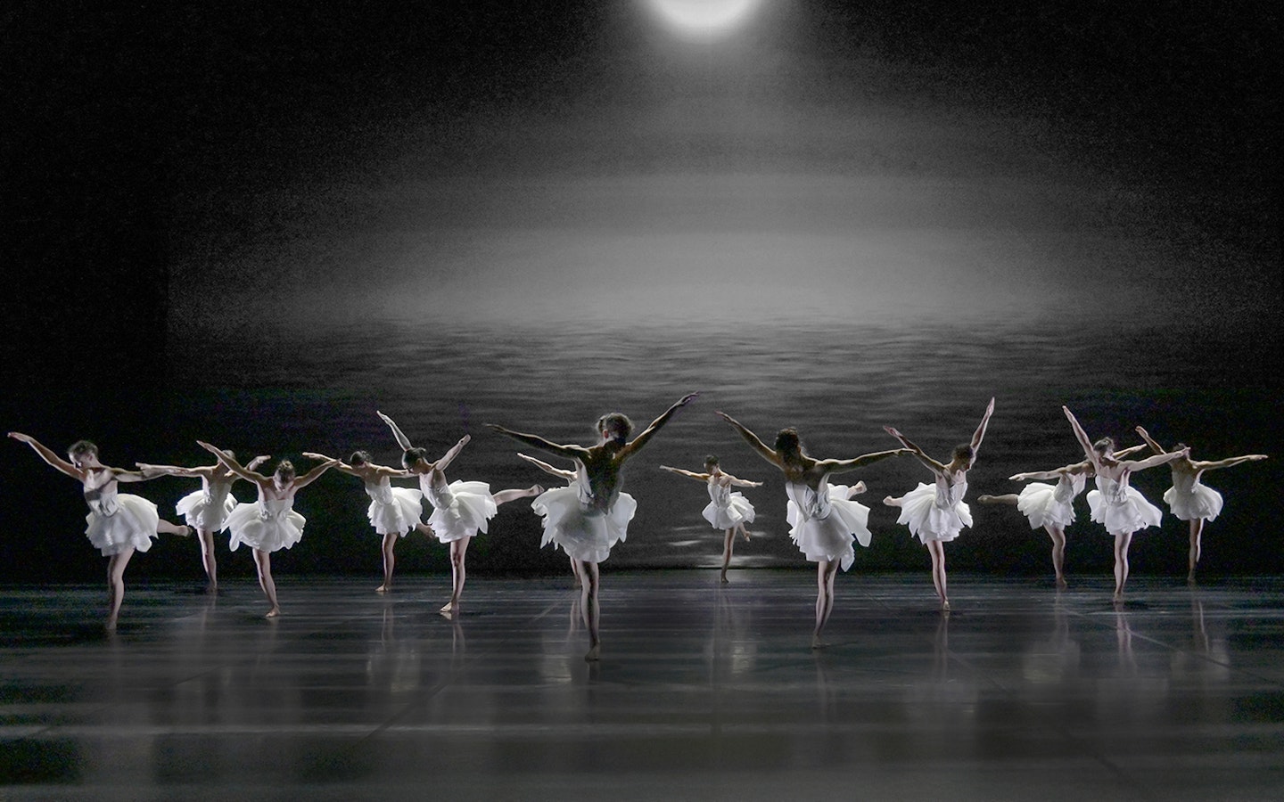 Ballet dancers performing Swan Lake by Preljocaj on a dimly lit stage.