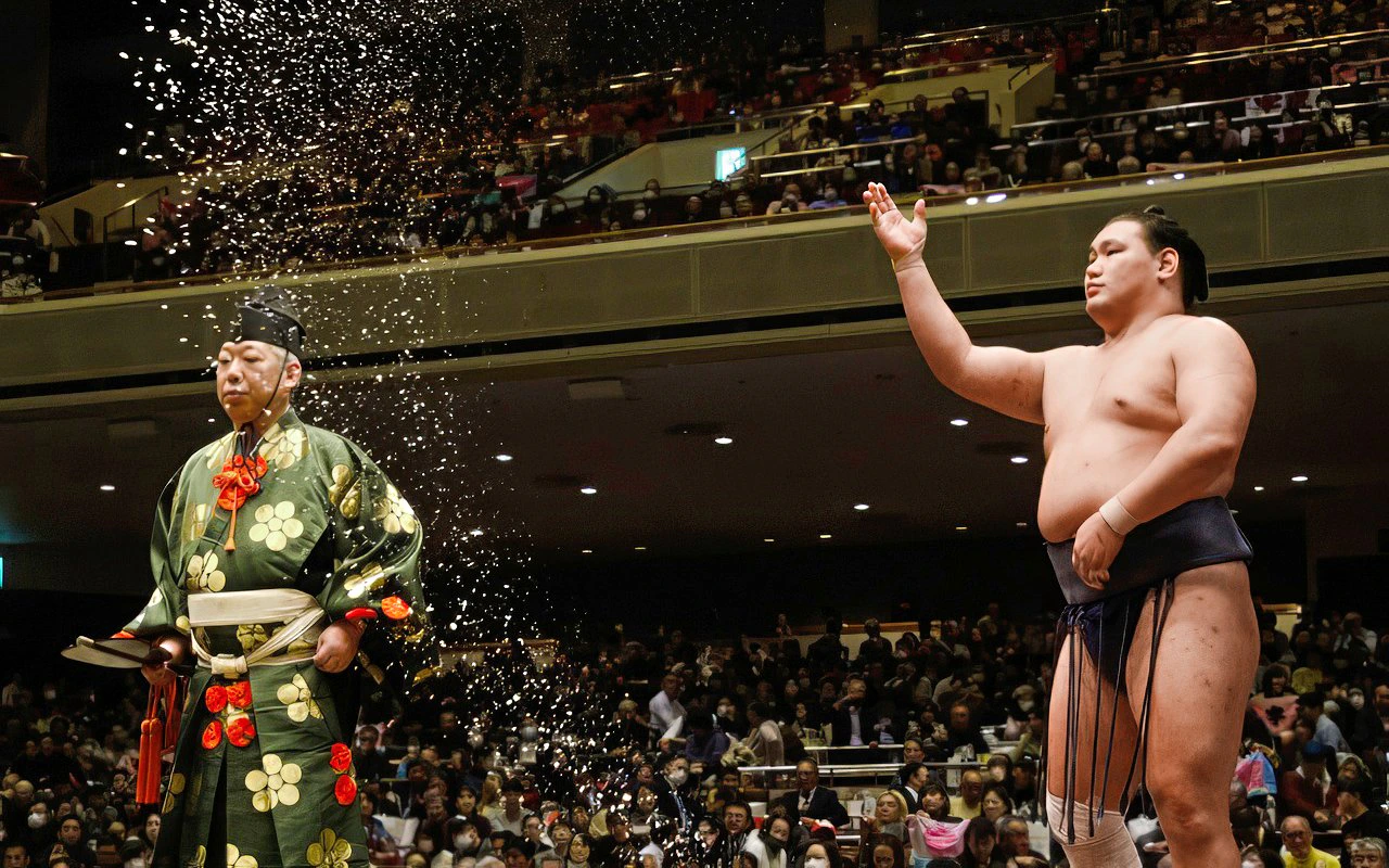 Sumo wrestler throwing salt during a traditional ceremony in Japan.
