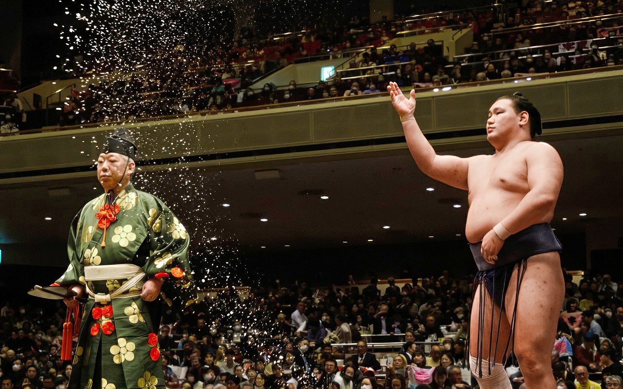 Sumo wrestler throwing salt during a traditional ceremony in Japan.