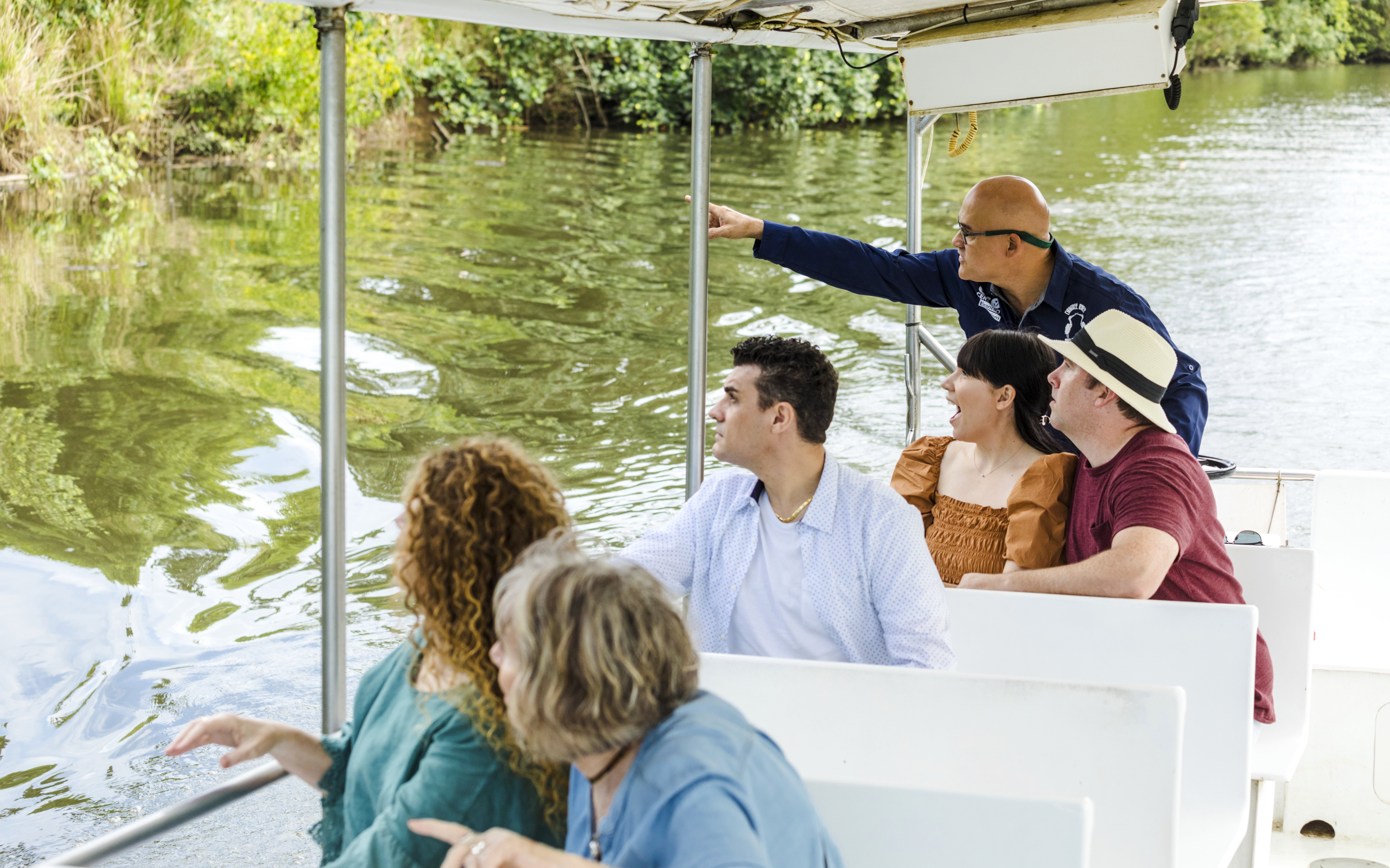 Tourists on a river cruise with Billy Tea Safaris in Daintree, observing wildlife.