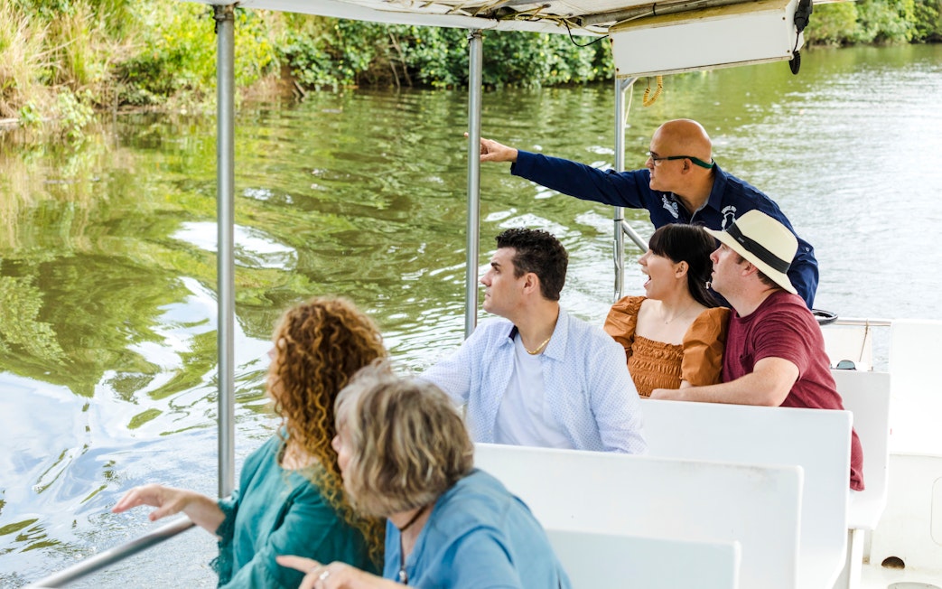 Tourists on a river cruise with Billy Tea Safaris in Daintree, observing wildlife.