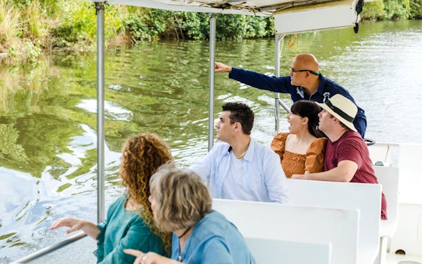 Tourists on a river cruise with Billy Tea Safaris in Daintree, observing wildlife.