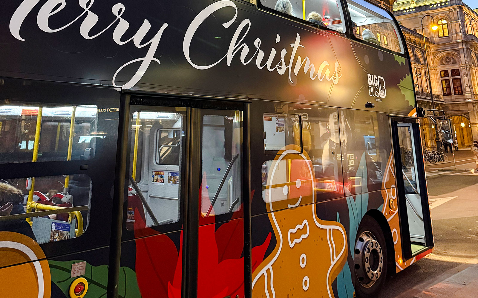 Big Bus HOHO decorated with Christmas theme and gingerbread design in city street.