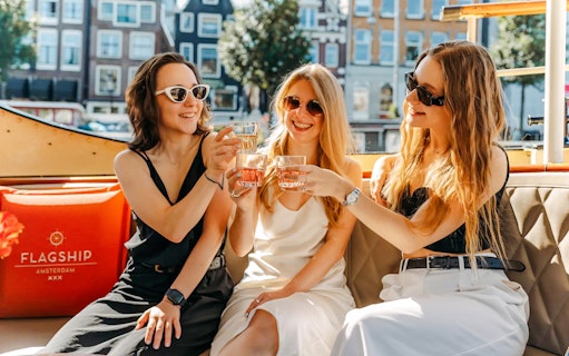 Tourists toasting drinks on a canal cruise in Amsterdam.