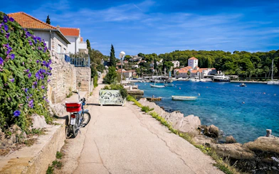 Pathway along Maslinica harbor with boats and stone houses, part of Trogir's Blue Lagoon tour.