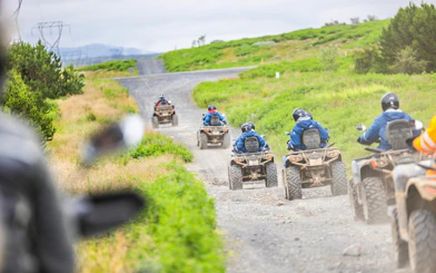 ATVs on gravel path during Twin Peaks tour near Reykjavik, surrounded by green landscape.