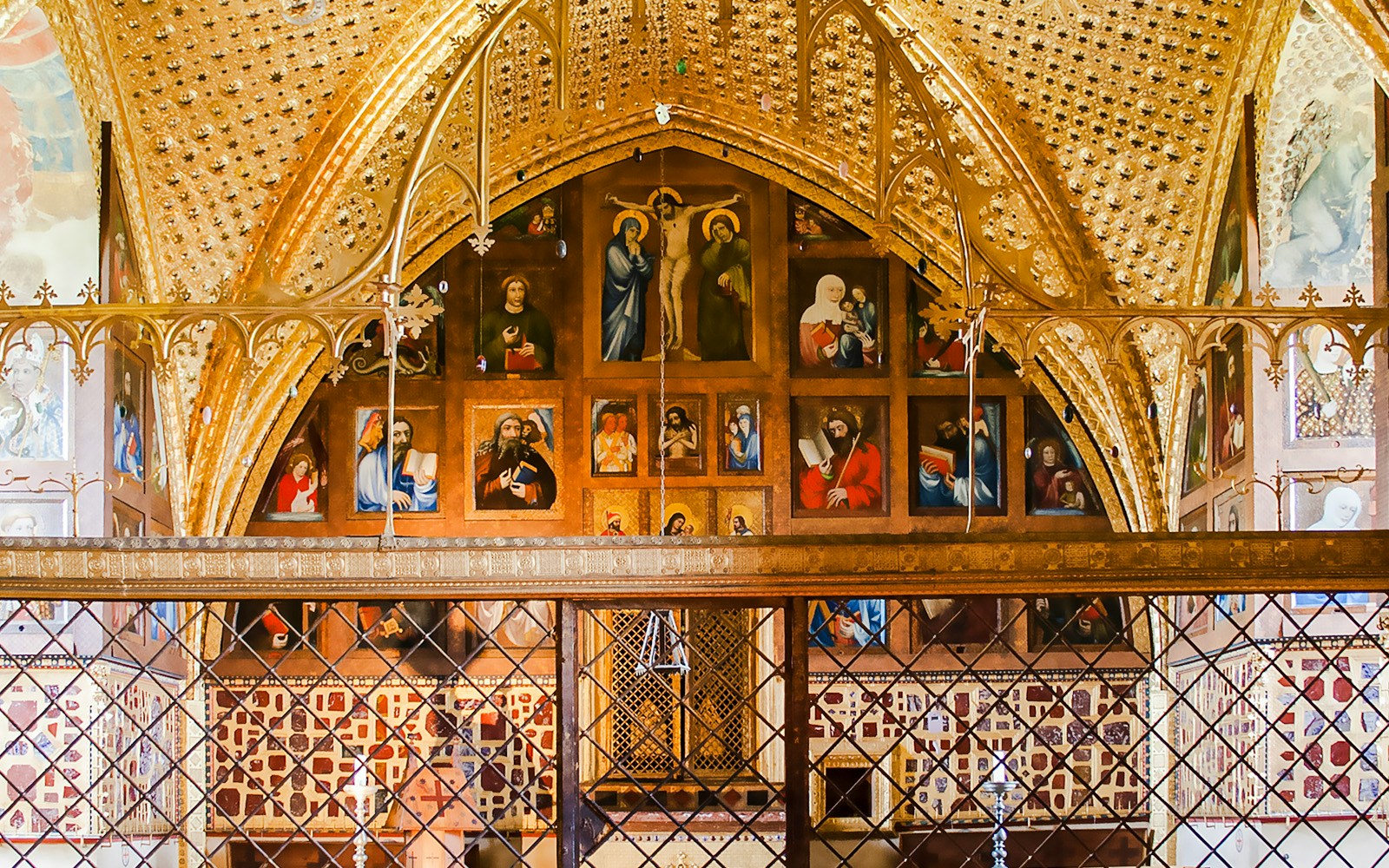 Interior of the Chapel of the Holy Cross at Karlstejn Castle, featuring religious paintings and ornate gold detailing.
