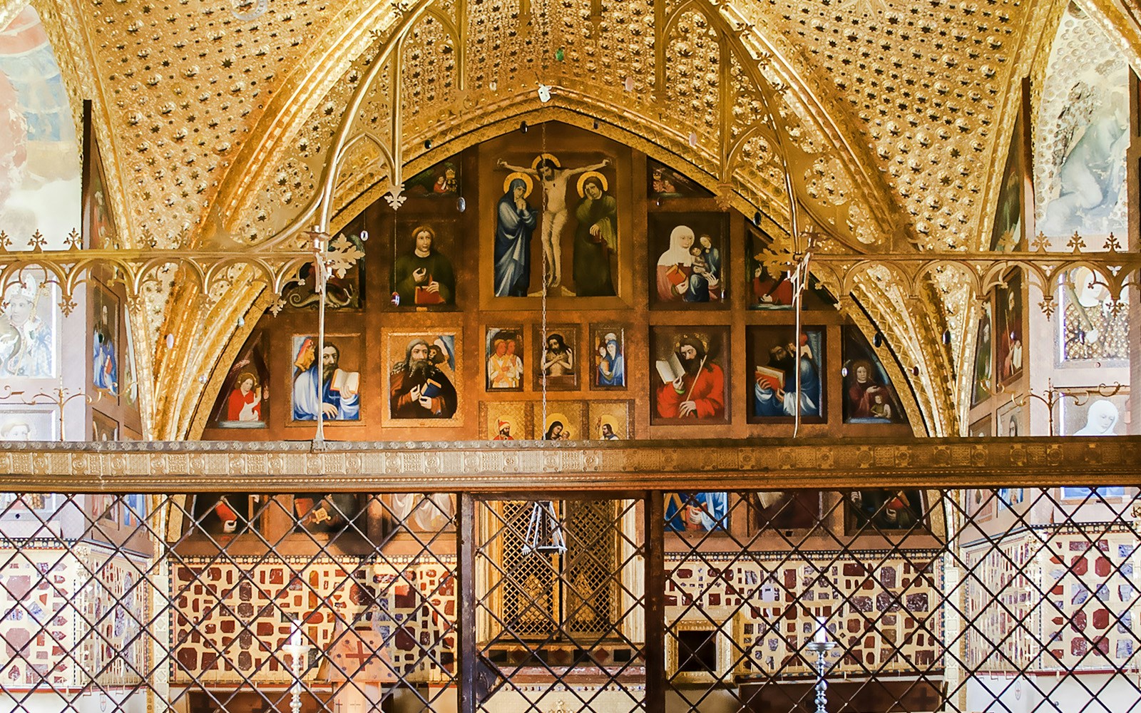 Interior of the Chapel of the Holy Cross at Karlstejn Castle, featuring religious paintings and ornate gold detailing.