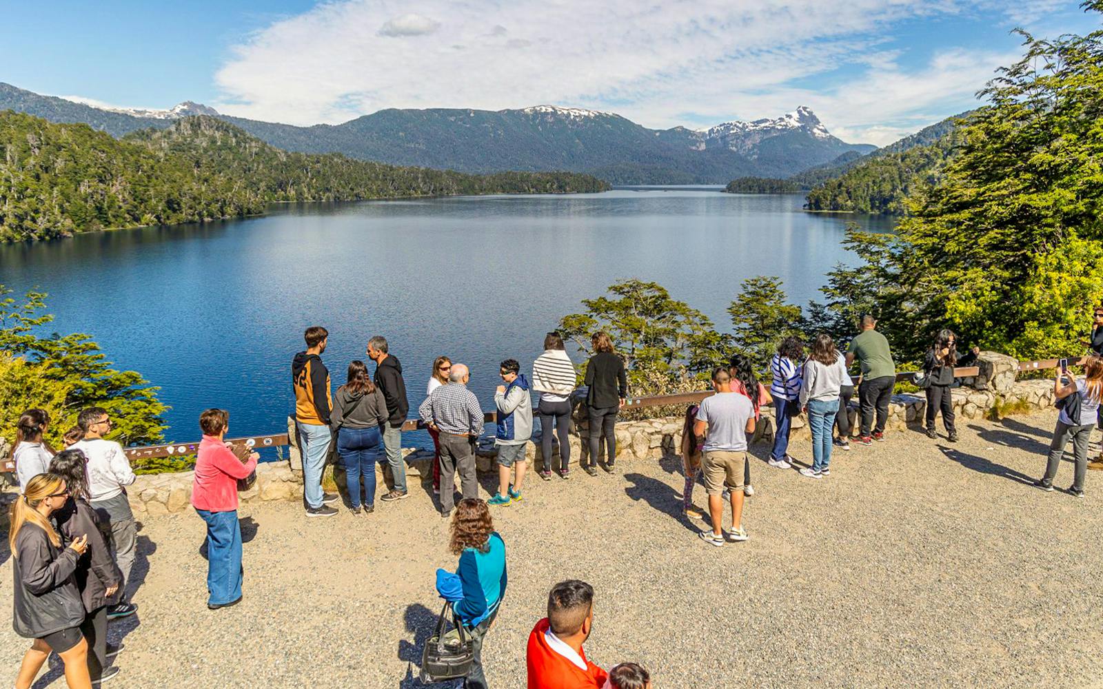 Visitors at a viewpoint overlooking Patagonian lakes and mountains.