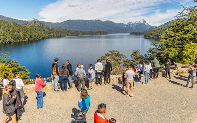 Visitors at a viewpoint overlooking Patagonian lakes and mountains.