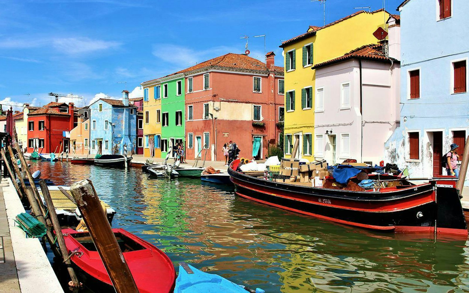 Vibrant homes along a canal in Burano, Italy, with colorful facades and boats.