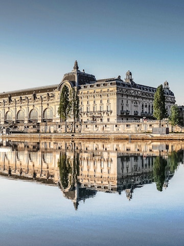 Musée d'Orsay reflecting in the Seine River, Paris, featured in Emily in Paris Tours.