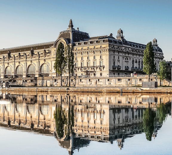 Musée d'Orsay reflecting in the Seine River, Paris, featured in Emily in Paris Tours.