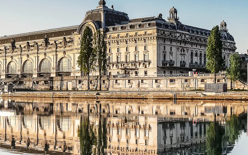 Musée d'Orsay reflecting in the Seine River, Paris, featured in Emily in Paris Tours.