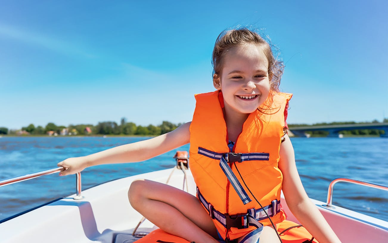 Child enjoying a guided boat tour in Dubai, wearing a life jacket.