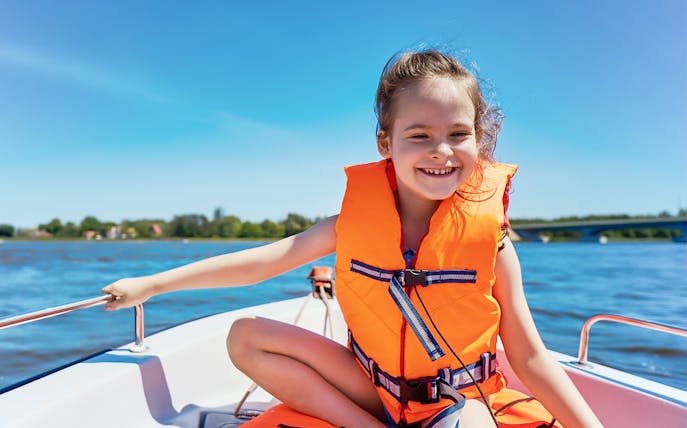 Child enjoying a guided boat tour in Dubai, wearing a life jacket.