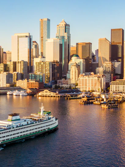 Seattle skyline with ferry on water at sunset.