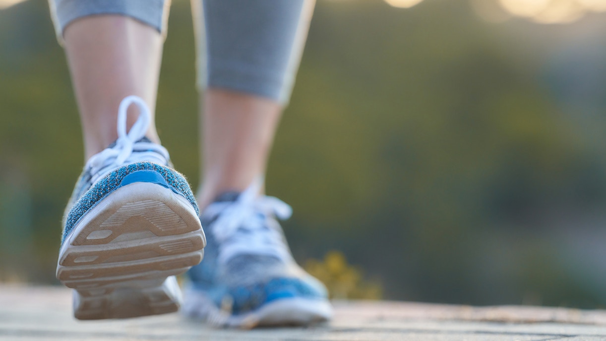 Walking tour in nature with close-up of sneakers on a path.
