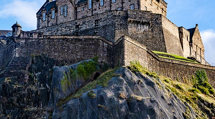 Edinburgh Castle atop Castle Rock under a clear blue sky.
