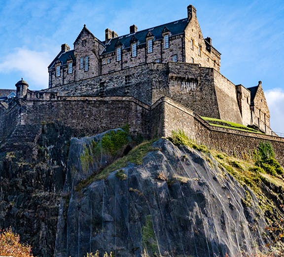 Edinburgh Castle atop Castle Rock under a clear blue sky.