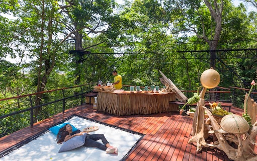 Woman relaxing on a deck in a forest setting, Phuket, Thailand.