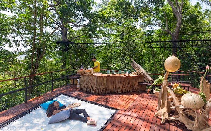 Woman relaxing on a deck in a forest setting, Phuket, Thailand.
