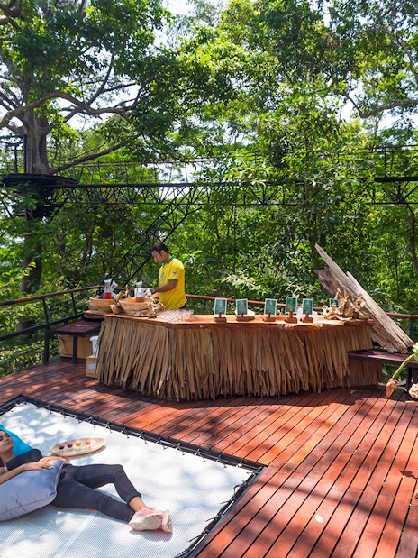 Woman relaxing on a deck in a forest setting, Phuket, Thailand.