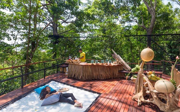 Woman relaxing on a deck in a forest setting, Phuket, Thailand.