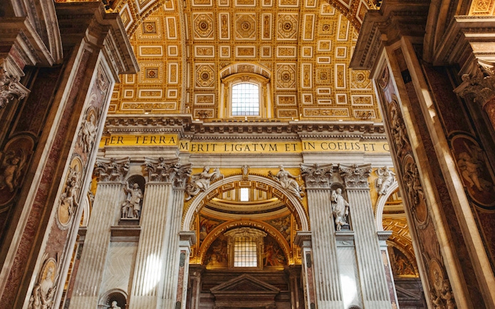 Interior view of St. Peter’s Basilica with ornate columns and detailed ceiling.