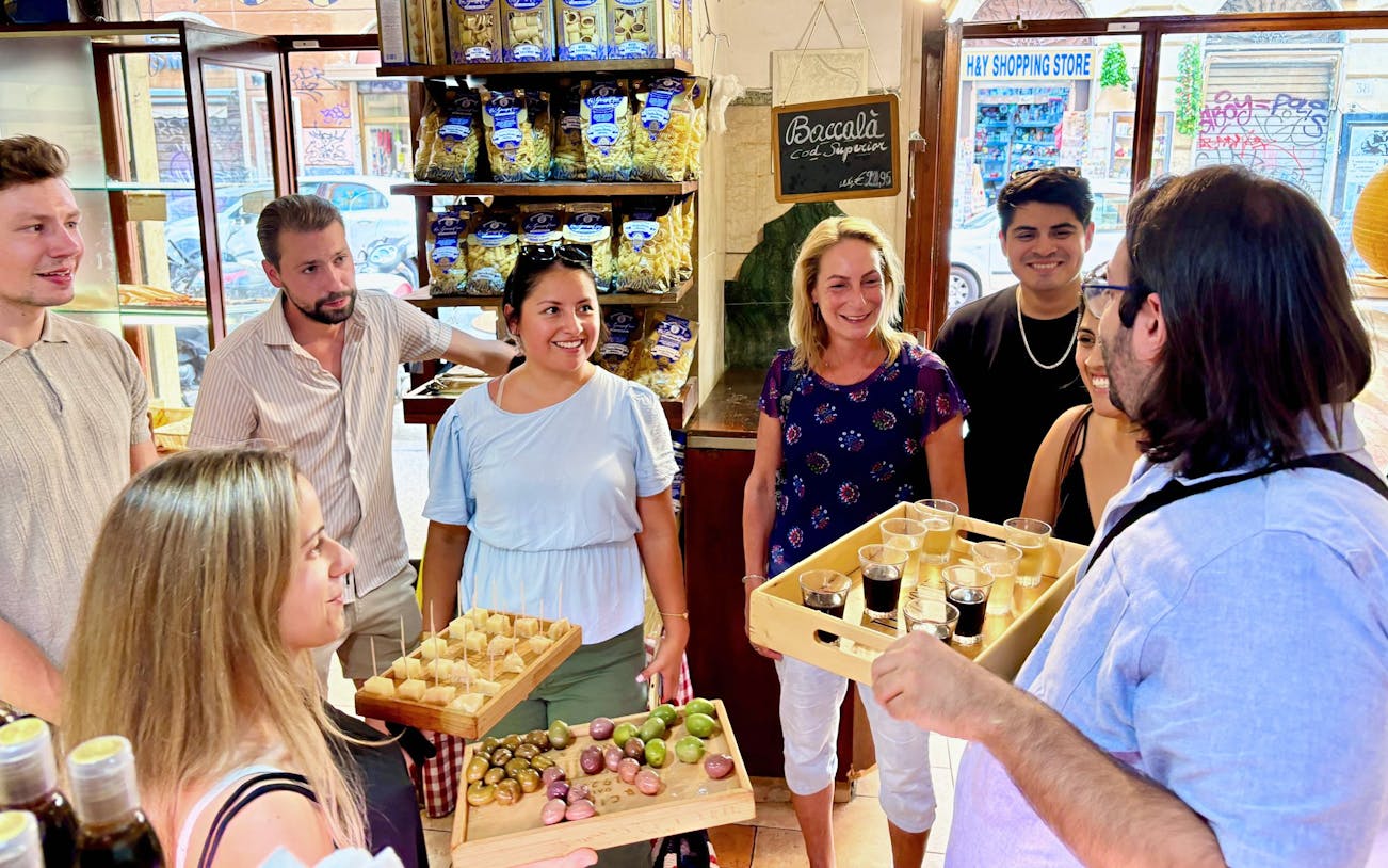 Tour group enjoying wine and food tasting in a Trastevere shop, Rome.