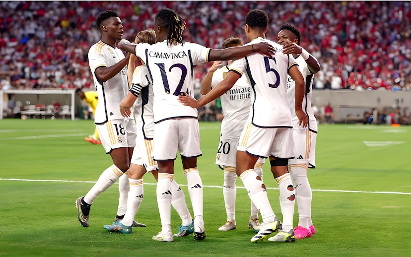 Soccer players in white jerseys huddling on a field during a match.