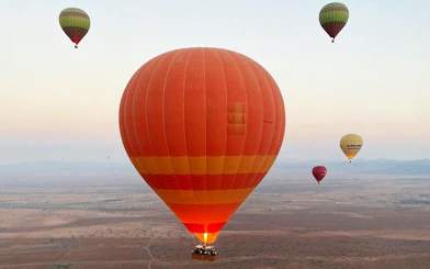 Hot air balloons floating over Marrakesh desert at sunrise.