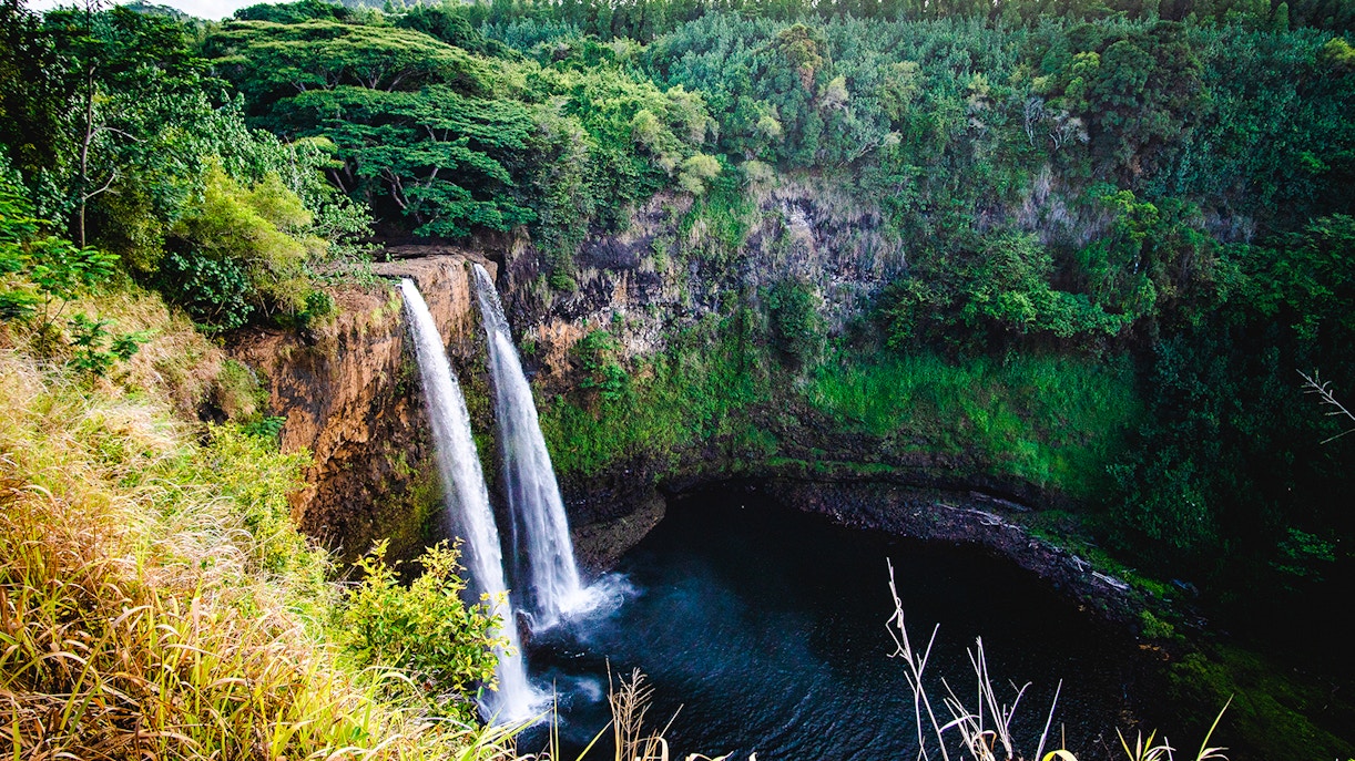 Wailua Falls cascading into a lush green valley in Kauai, Hawaii.