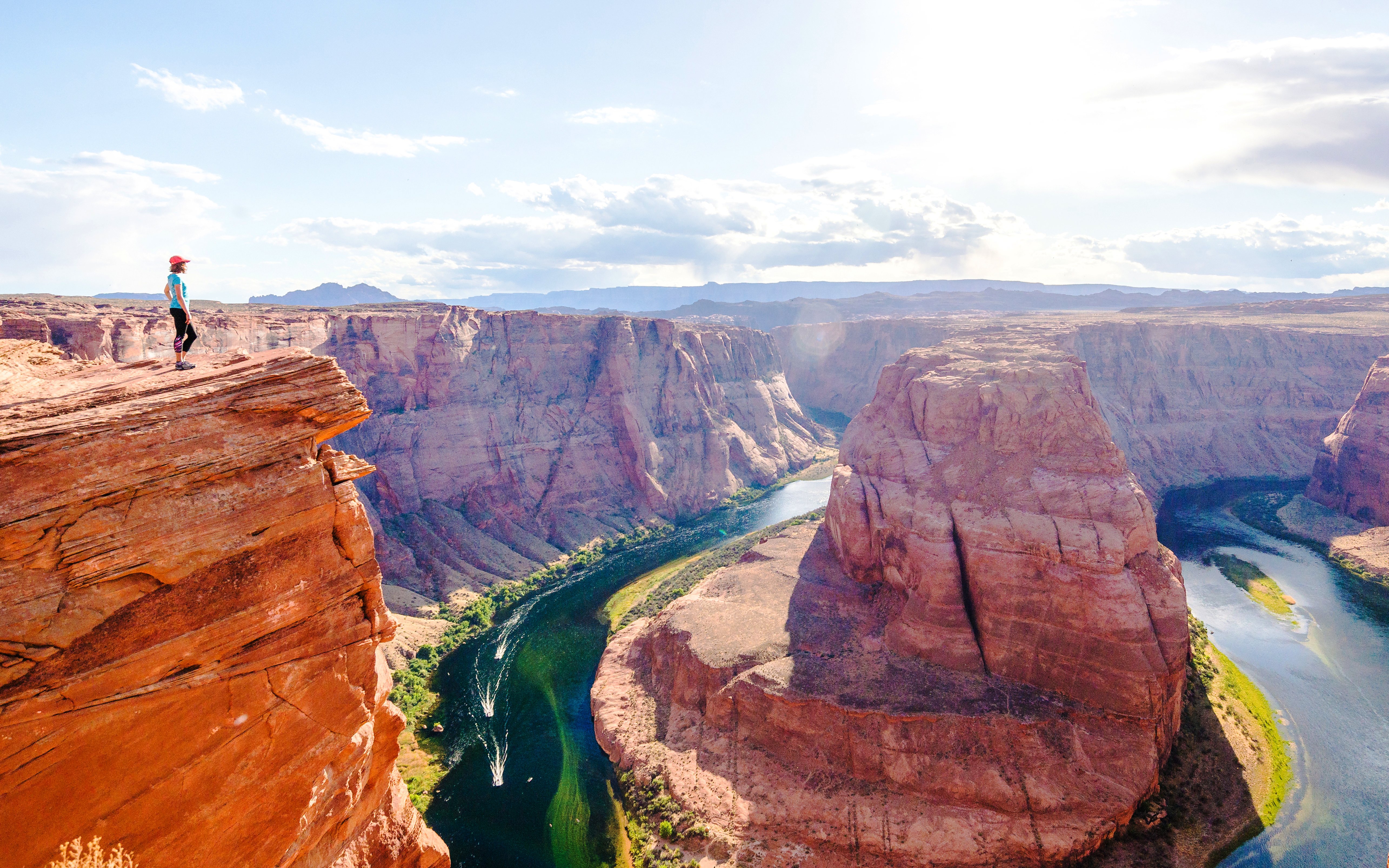 Woman standing on cliff edge overlooking Horseshoe Bend, Arizona.