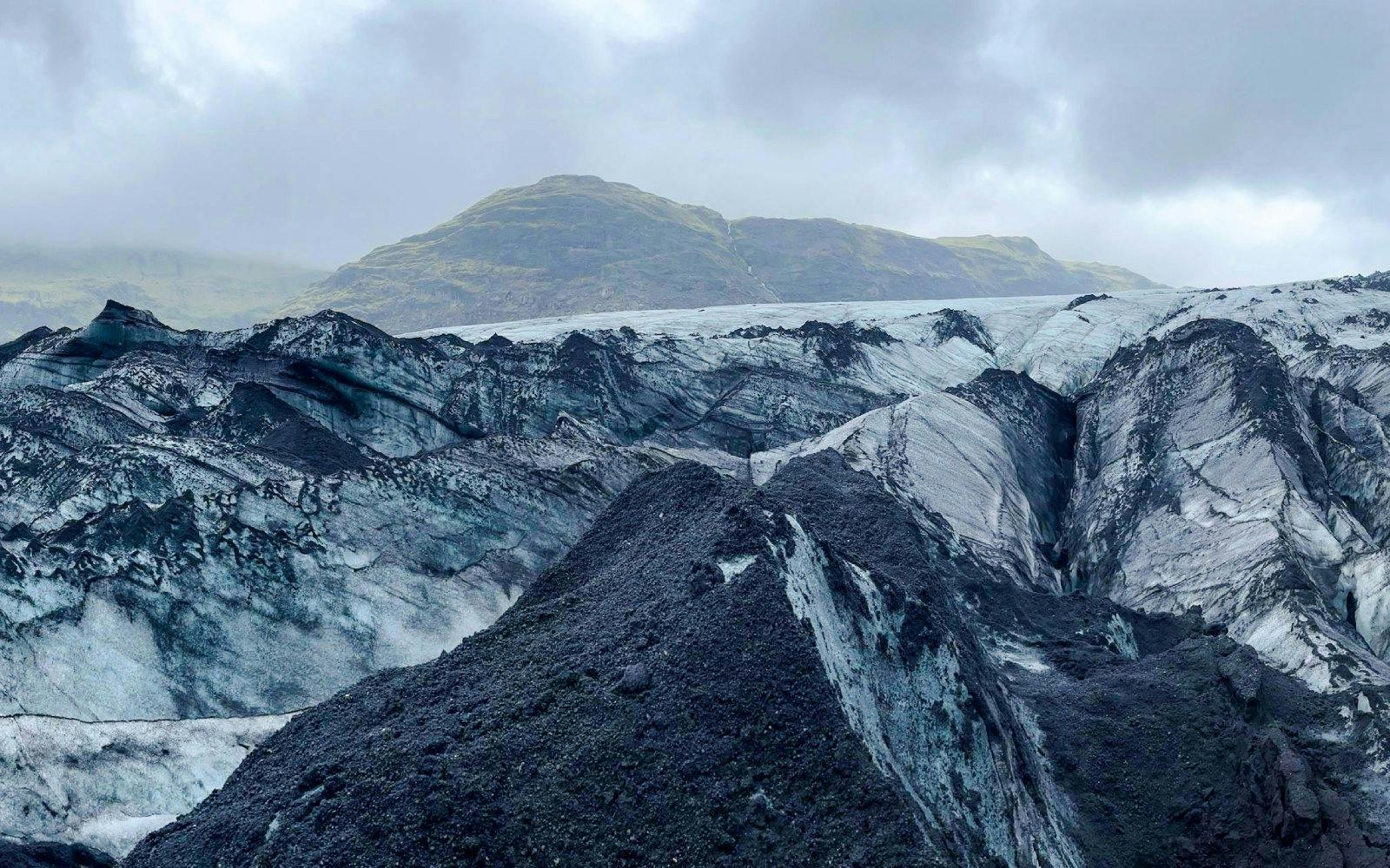 Guests hiking on Sólheimajökull Glacier in Iceland with mountainous backdrop.
