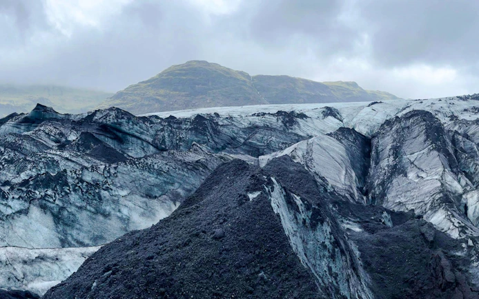 Guests hiking on Sólheimajökull Glacier in Iceland with mountainous backdrop.