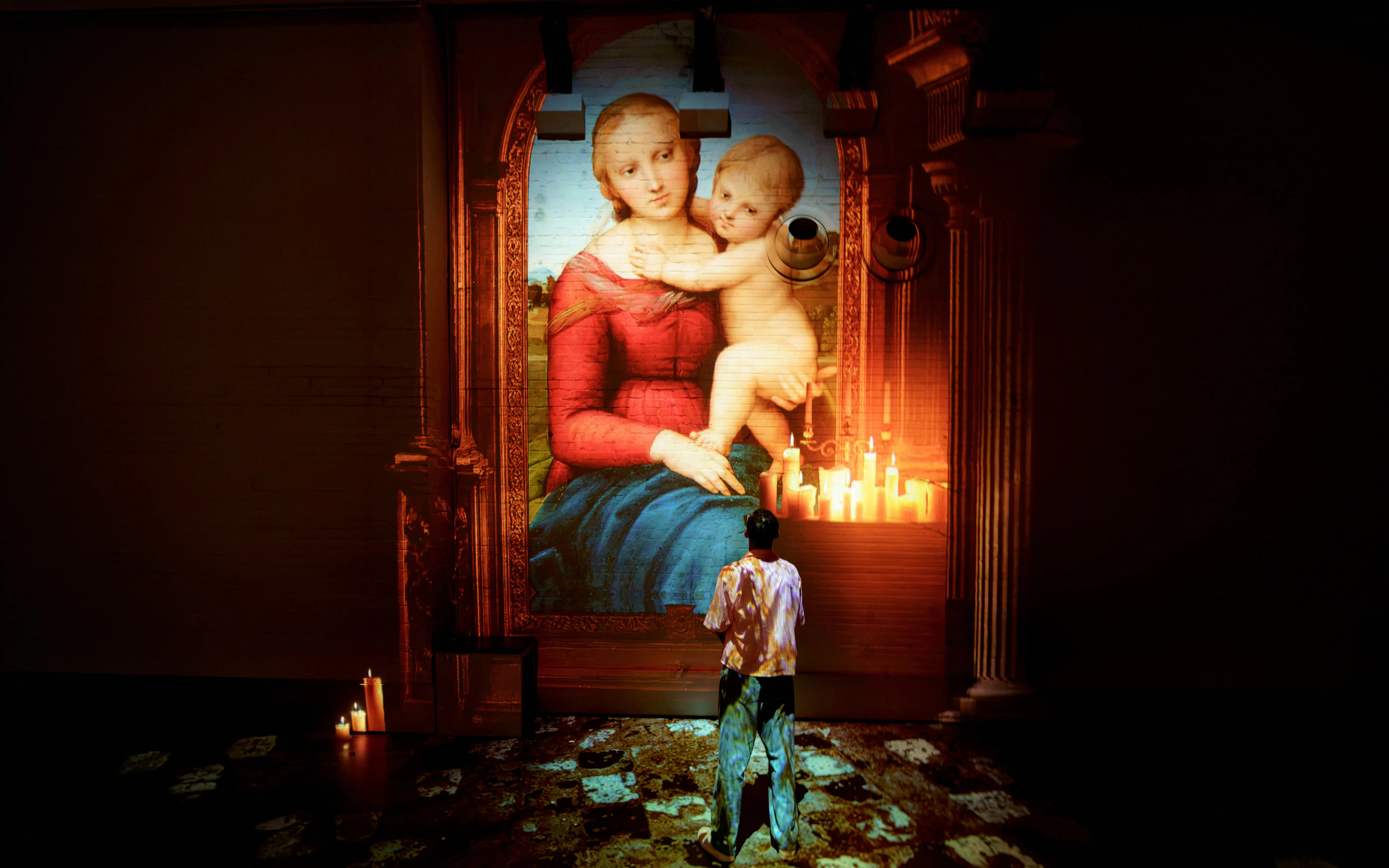 Visitor viewing Raphael's Madonna projection at Fabrique des Lumières exhibit.