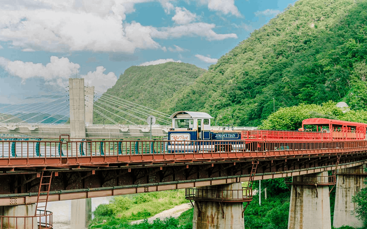 Aerial view of Gangchon Gimnyujeong Rail Bike on a bridge with mountains in the background.