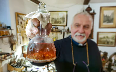 Man holding amber-filled flask at Gdańsk Amber Workshop.